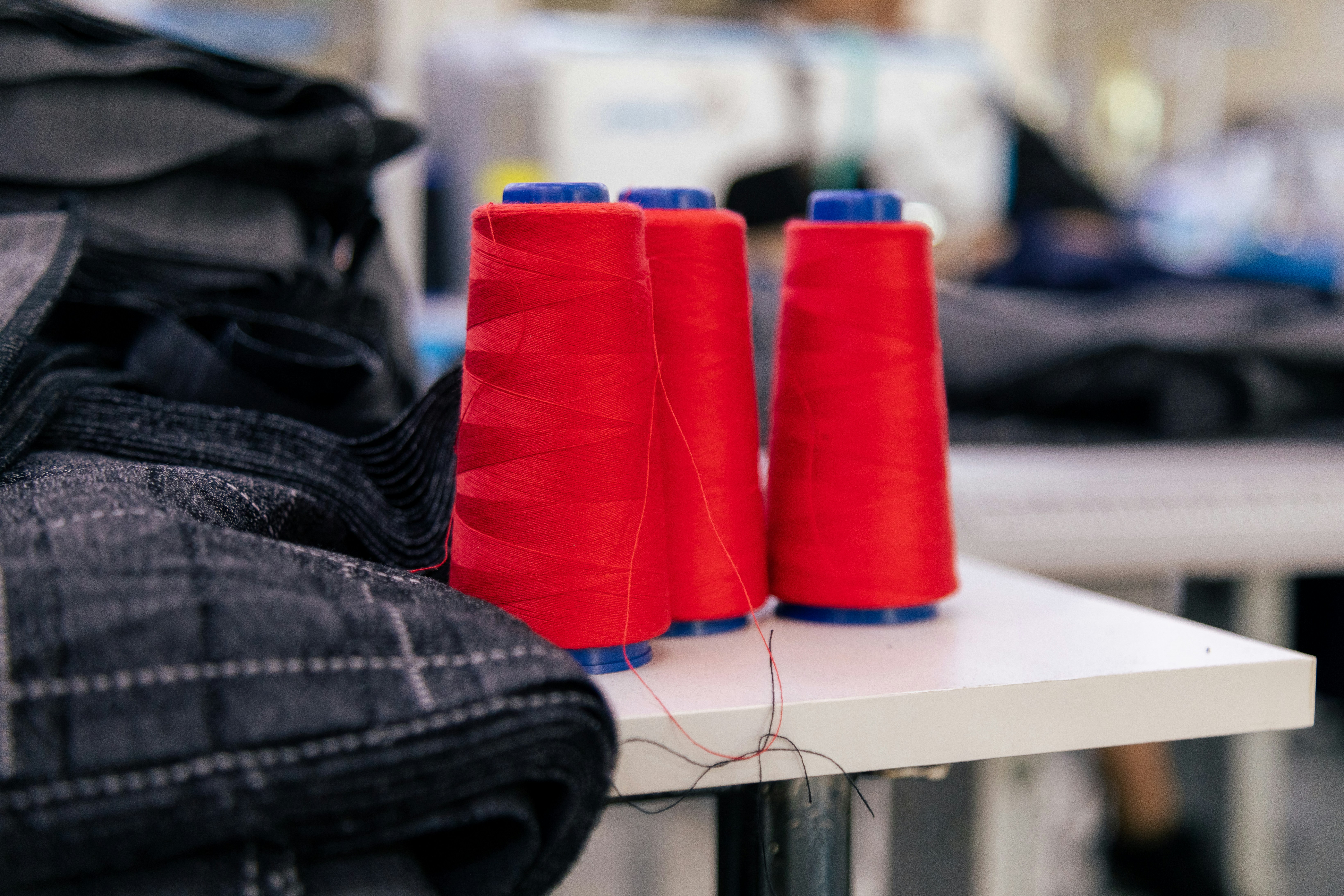 Red thread spools next to dark fabric in a garment factory